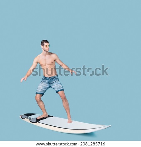 Athletic man riding a surfboard. Summer sport activity. Surfer movements on blue studio background.