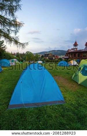 Colorful tourist tents in the mountains, bunch of colorful camps in a field during early morning.