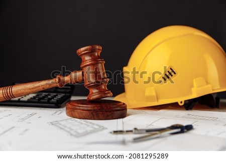 Judge wooden gavel and yellow helmet with construction plans