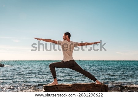 Attractive young man practicing yoga meditation and breathwork outdoors by the sea Royalty-Free Stock Photo #2081298622