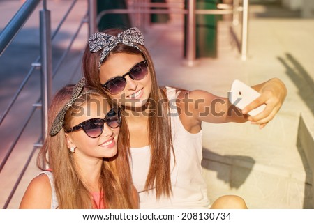 two girls  taking photos with a telephone