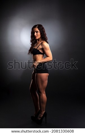 Portrait of Strong fitness woman bodybuilder with black hair and tanned body.