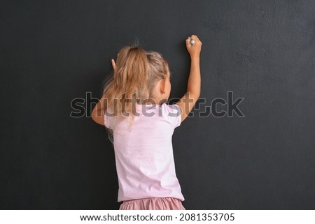 Cute little girl drawing on black wall