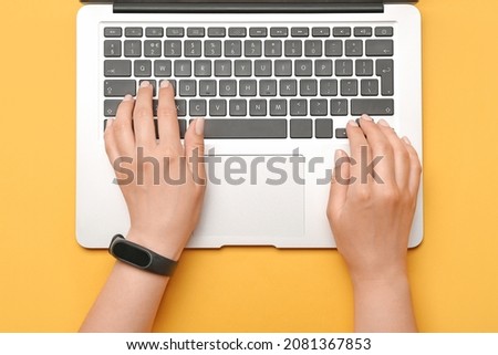 Woman working on laptop on color background