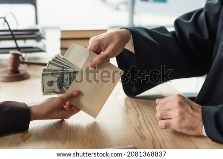 partial view of woman giving money in envelope to judge, anti-corruption concept