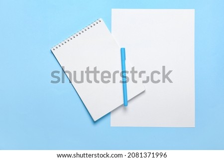 Blank paper sheet, notebook and pen on color background