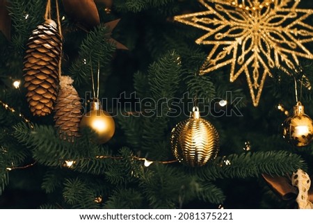 Golden Christmas decorations of the Christmas tree in close-up.New Year's background.Selective focus with shallow depth of field.
