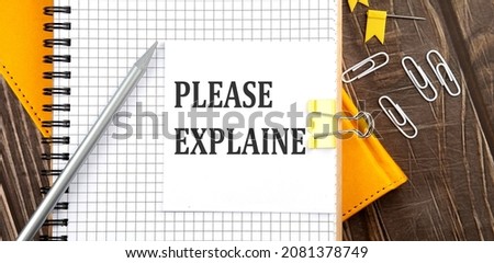 PLEASE EXPLAIN text on a sticker on notebook, wooden background