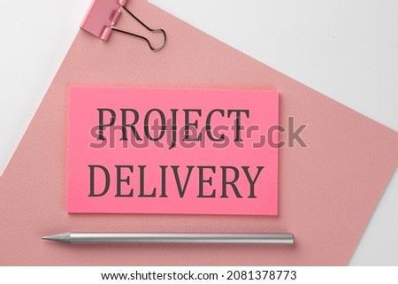 Pink sticker on pink paper with pencil on a white background , text PROJECT DELIVERY