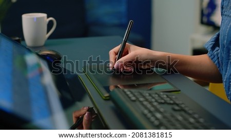Close up of hand holding stylus on graphic tablet for retouch work. Woman photographer using editing app for pictures retouching at photography studio. Image editor with devices