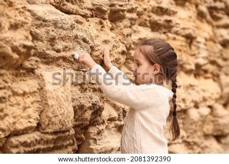 Little girl placing note in the Wailing Wall Royalty-Free Stock Photo #2081392390