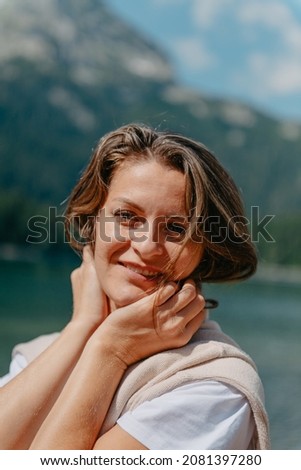 The girl looks at the Black Lake, forest and mountains in the Durmitor National Park of Montenegro. A tourist enjoys a magical view of the lake, a coniferous forest and a magical view, sitting on a