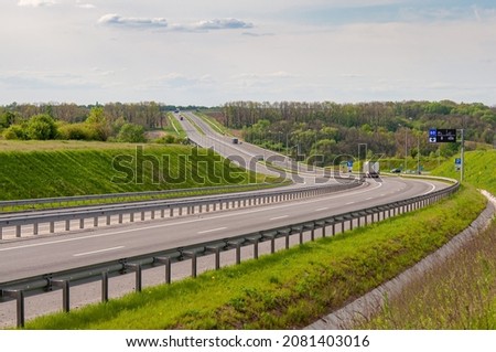 Highway with ascent and descent, bumpers and road signs. Trucks are moving along Royalty-Free Stock Photo #2081403016