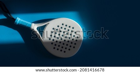 White professional paddle tennis racket with natural lighting on blue background. Horizontal sport theme poster, greeting cards, headers, website and app Royalty-Free Stock Photo #2081416678