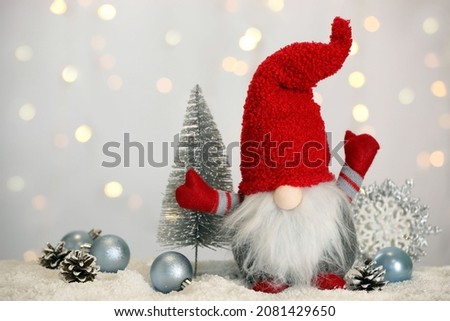 Cute Christmas gnome and festive decor on snow against blurred lights