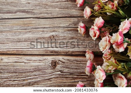 Pink roses flowers border frame on wooden background