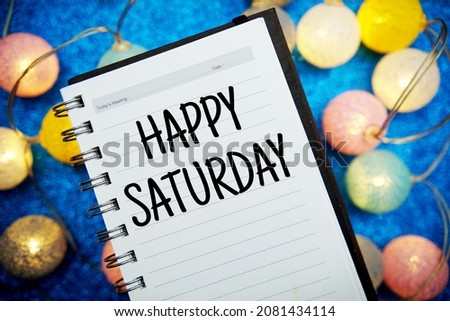 Happy Saturday text notepad mockup and LED cotton balls decoration on blue bokeh background