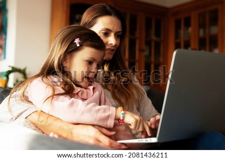 Cheerful little girl using laptop. Beautiful girl watching cartoon on laptop