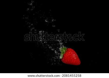 Strawberry falling in water on black background