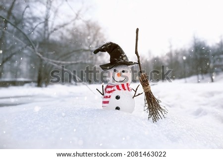 winter nature background. Snowman toy in witch hat with broom on snow. Christmas, New Year holidays. festive winter season. cold snowy weather. copy space