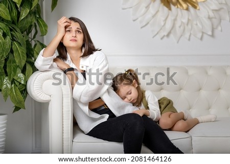 Tired mother suffering from experiencing depression and her sleeping kid. Motherhood mental health care. Royalty-Free Stock Photo #2081464126