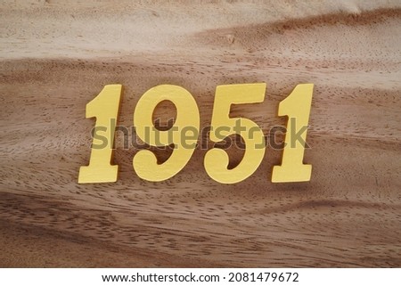 Golden Arabic numerals 1951 on a dark brown to white wood grain background.