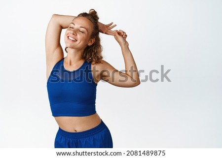 Happy active fitness woman stretching and warming up before exercises, smiling pleased after jogging. Energetic funner looking motivated, white background