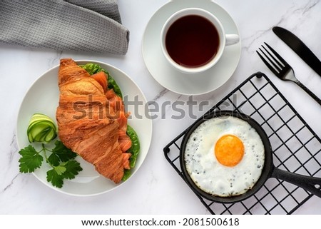 Food photography of breakfast, croissant, fried egg, tea, salmon sandwich