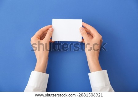 Female hands with blank paper on color background