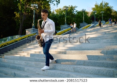 Saxophonist plays the saxophone on stairs in park