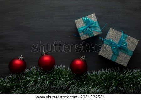 black wooden christmas background with red spheres and gifts with blue bow