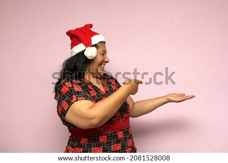 Body positive Latina adult woman wears Christmas hat and shows her enthusiasm for the arrival of December and Christmas
