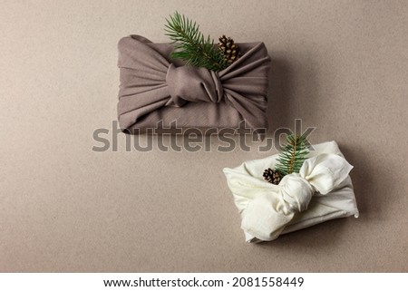 Japanese wrapping cloth Furoshiki, traditionally used to transport gifts. Present boxes with fir, pine cones, cinnamon and rose hips. Zero waste concept. Royalty-Free Stock Photo #2081558449