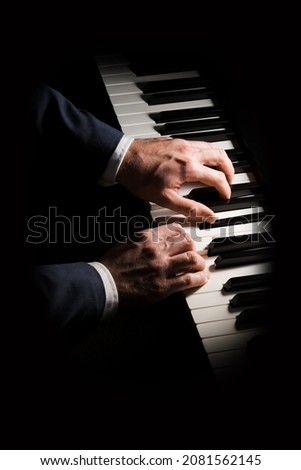Pianist plays chord on piano with both hands. Touches gently the keyboard. White, male, mature hands. 