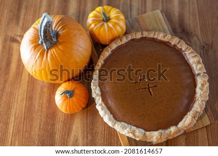 Newly baked pumpkin pie surrounded by pumpkins