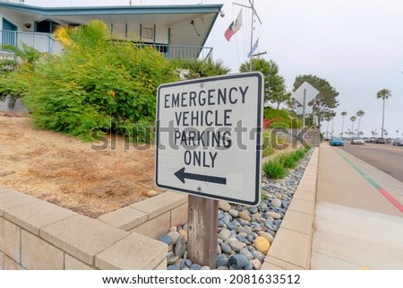 Emergency vehicle parking only sign post outside a building in Oceanside, California
