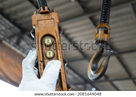 Industrial control buttons. hand holding overhead cranes remote. Up Down hydraulic controller switch. electric remote push button switch of hoist lift or crane for control direction. Royalty-Free Stock Photo #2081644048