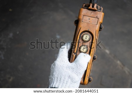 Industrial control buttons. hand holding overhead cranes remote. Up Down hydraulic controller switch. electric remote push button switch of hoist lift or crane for control direction. Royalty-Free Stock Photo #2081644051