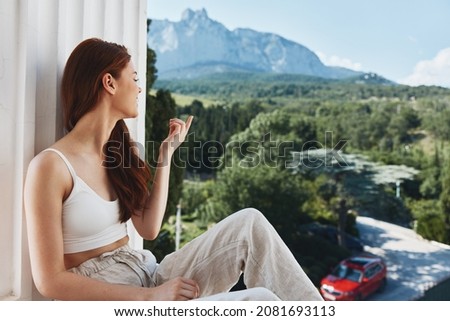 Portrait woman with long hair on an open balcony Green nature summer day Relaxation concept