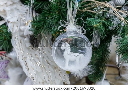 White horse in a transparent christmas tree ball, festive Christmas decoration with imitation of snow, sparkling background