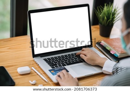 Businesswoman shopping online using a laptop blank white screen and credit card at the office.