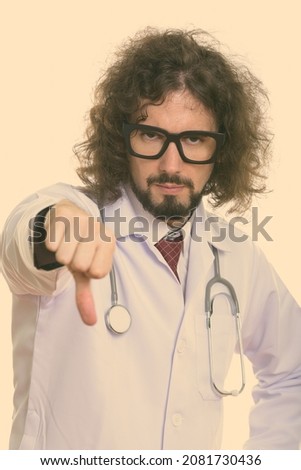 Studio shot of handsome bearded man doctor with curly hair isolated against white background