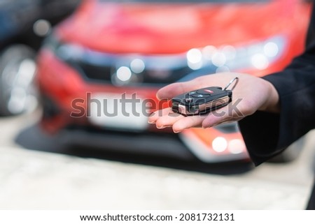 Sale agent holding car keys with car on background, rent car and car insurance concept.