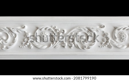 A fragment of a white plaster ceiling molding with an ornament. Isolated on black, close-up Royalty-Free Stock Photo #2081799190