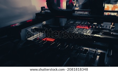 Production of high-tech computer chips on an automatic SMT machine. Digital technologies for automation of industry. Red neon lights illuminate Chip Components for automation test. Royalty-Free Stock Photo #2081818348