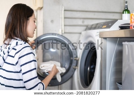 A woman using a drum-type washing machine Royalty-Free Stock Photo #2081820277