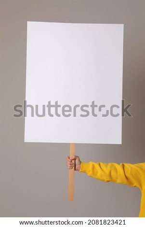 Woman holding blank sign on light grey background, closeup. Space for design