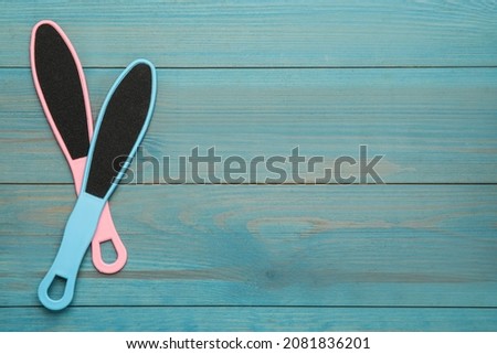 Colorful foot files on light blue wooden table, flat lay with space for text. Pedicure tools