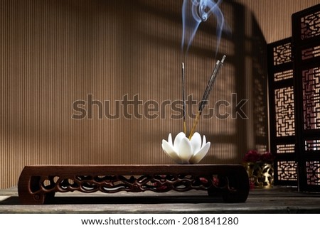 Smoke from burning incense sticks standing on lotus incense holder Royalty-Free Stock Photo #2081841280