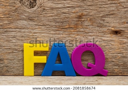 Acronym FAQ made of color plastic letters on wood background. A frequently asked questions.